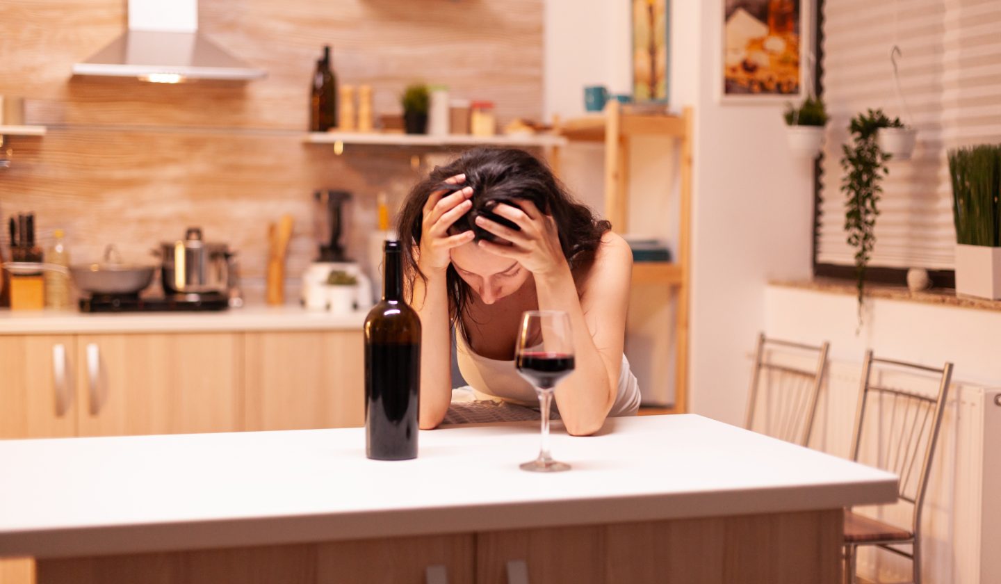 Funkcionālais alkoholisms: sieviete pie galda ar vīna glāzi